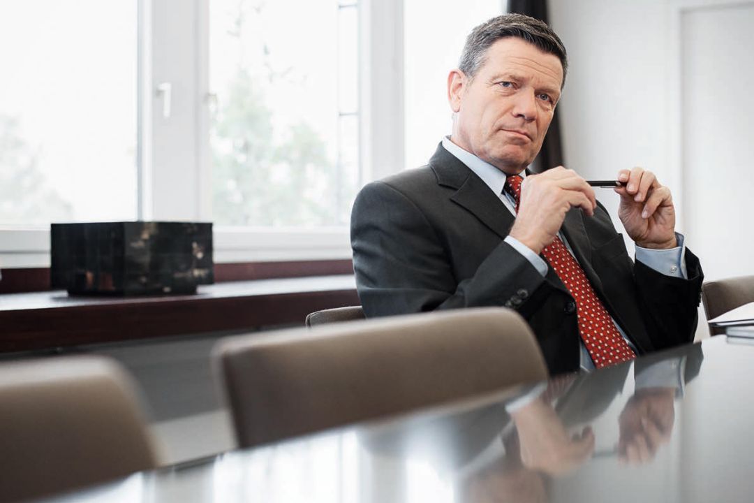 Business man holding a pen while sitting at a table